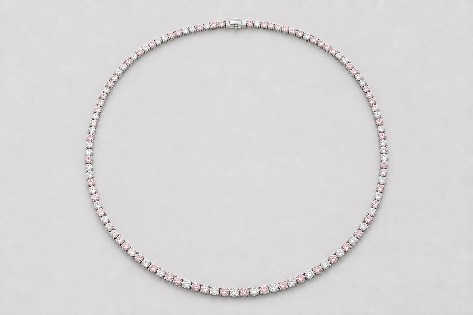 A pink and white gemstone tennis necklace shown from above